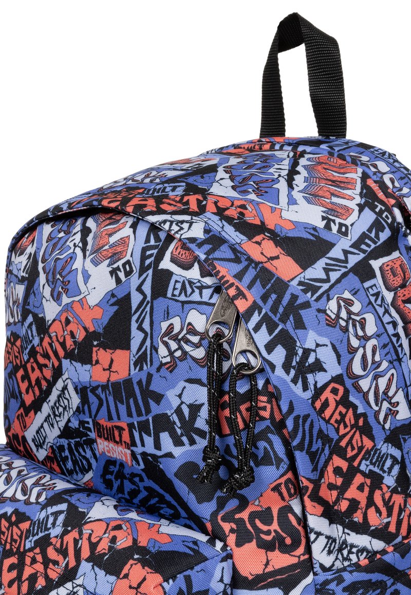 Le sac à dos présente un motif graphique en bleu, rouge et noir, fabriqué en tissu durable. Il comprend des tirettes à double zip et une poignée supérieure.