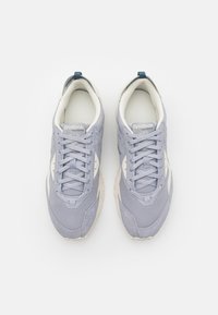 Světlé šedé sportovní boty z textilu s texturovaným povrchem, bílé detaily, kulaté tkaničky a polstrovaný límec.