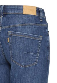 Rückansicht von blauen Jeans aus Denim mit einer aufgenähten Gesäßtasche und einem braunen Lederetikett mit der Marke "PULZ JEANS" am Bund.