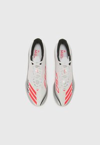 White soccer cleats with red accents and black trim, featuring a streamlined design, laces, and distinct F50 branding on the sides.