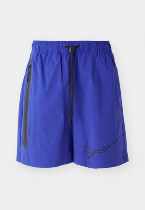 Blue athletic shorts with an elastic waistband and drawstring. Features side pockets, a smooth texture, and a black dotted Nike logo.