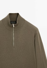 Dark olive zip-neck pullover made of 100% merino wool, featuring a ribbed collar and a sleek metal zipper detail at the front.