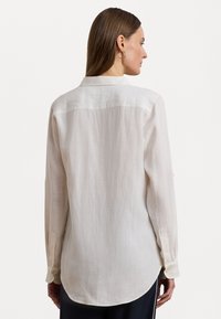 Light beige long-sleeve shirt made of linen with a slightly textured finish, featuring a button-down collar and rounded hem.