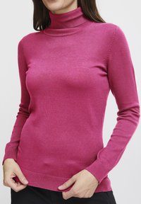 Pull à col montant ajusté en rose vif, avec des manches longues et un ourlet et des poignets côtelés. Fabriqué en matériau doux et léger.