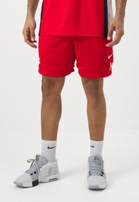 Røde nett atletiske shorts med sidelommer, med en hvit logo foran. Kombinert med grå basketballsko og hvite sokker.
