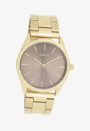 Montre-bracelet en métal doré avec un boîtier rond, un cadran dégradé marron, des indices horaires minimalistes et un bracelet en métal relié. Nom de la marque "OOZOO" visible.
