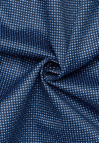 Tessuto navy con un motivo geometrico di punti blu chiaro e marroni, texture liscia e una lieve lucentezza. Il tessuto è arricciato a spirale.