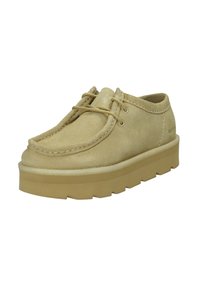 Scarpa beige in suede con lacci, punta tonda, dettagli cuciti e una suola in gomma spessa con un motivo di battistrada testurizzato.