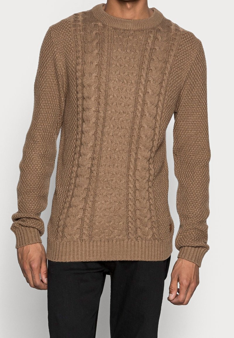 Maglione lavorato a maglia marrone con un motivo testurizzato e cavi alti. Collo e polsini a costine, realizzato con filato spesso per maggiore calore.