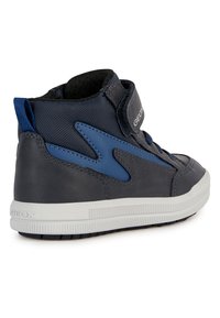 Sneaker alte di colore blu scuro con parte superiore in pelle liscia e tessuto. Caratterizzate da una cinghia a strappo e suola in gomma bianca. Visibile il marchio Geox.