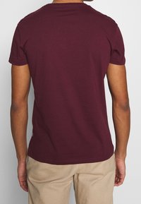 Bordeauxfarbener Baumwoll-T-Shirt mit kurzen Ärmeln, Rundhalsausschnitt und einer glatten Textur. Verfügt über minimale Nähte und keine sichtbaren Logos oder Akzente.