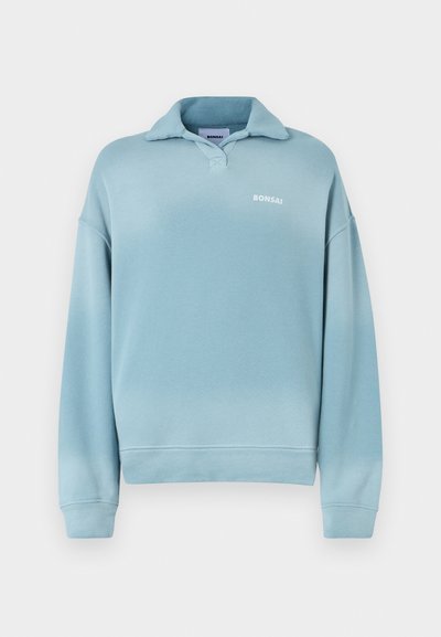 Απαλό μπλε φούτερ με κολάρο, μακριά μανίκια και ριμπμάνικια. Διαθέτει ένα μικρό λογότυπο "BONSAI" σε λευκό χρώμα στο στήθος.