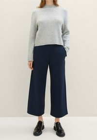 Šedý žebrovaný svetr s cropped designem, doplněný námořnickými širokými kalhotami. Černé šněrovací boty dovršují celý outfit.