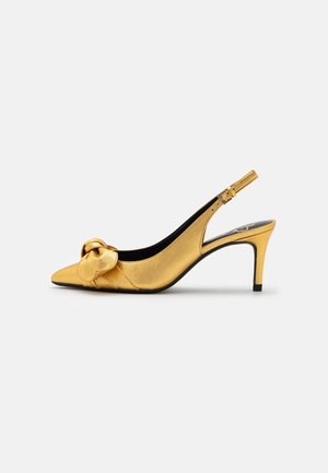 Chaussure à talons aiguilles en satin doré, avec un bout pointu et un détail noué à l'avant ; elle présente un talon élancé et une bride réglable.