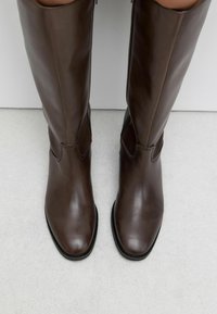 Ruske nahkate hlačne čizme s elegantnim dizajnom, šiljastim vrhom i suptilnim šavovima duž gornjeg dela. Ravni potplati.