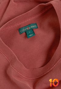 Maglione rosso a girocollo con etichetta verde "J.Crew Always" di taglia M cucita al collo, prodotto in Cina, piegato per mostrare l'etichetta.