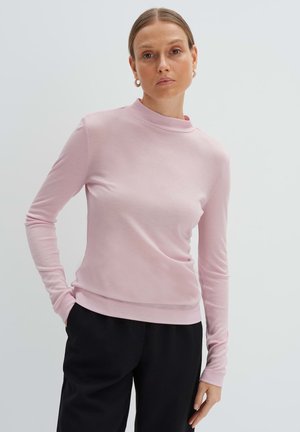 Light pink long-sleeve top with a high neckline, made from a smooth fabric. Features a fitted design and subtle stretch. Paired with black pants.