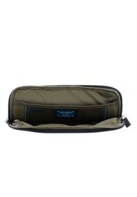 Portafoglio nero con chiusura a zip, esterno liscio, fodera interna verde oliva, scomparti multipli e etichetta con logo. Dettaglio della zip con grip testurizzato.