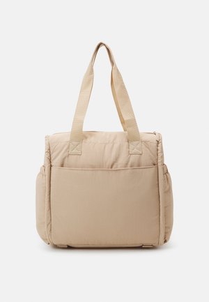 Beige gewatteerde tote bag met twee schouderriemen, voorzak en elastische zijvakken, weergegeven tegen een witte achtergrond.