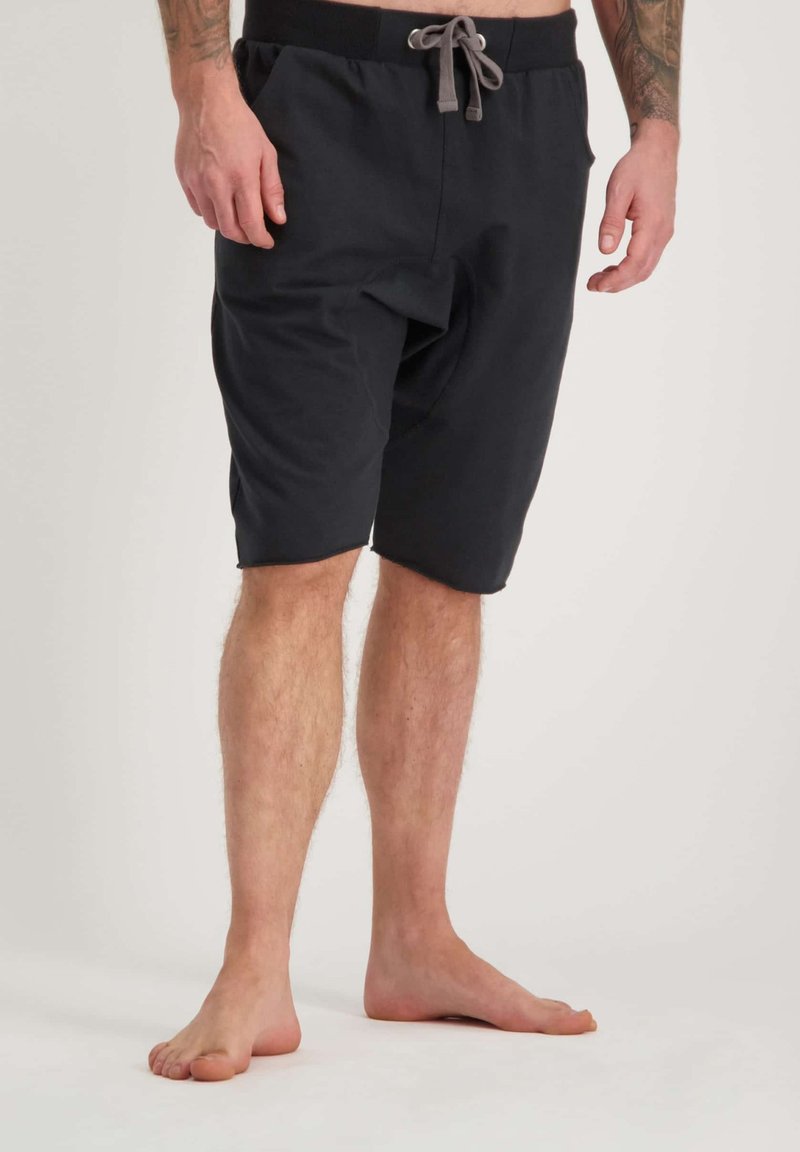 Shorts en coton noir avec une taille élastique et un cordon gris. Comprend des poches latérales et une coupe décontractée. S'arrêtent au-dessus du genou.