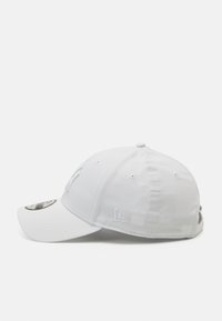 Boné de beisebol branco com aba curva, feito de um material suave. Apresenta um logotipo bordado na frente e costura icónica na lateral.