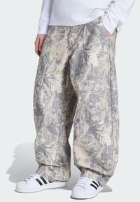 Kamouflage cargobukser i afdæmpede beige- og gråtoner med flere lommer og en løs pasform. Et tekstureret stof med løvmønstre.