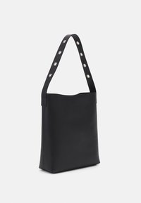 Sac en cuir noir avec une texture lisse, doté d'une large sangle avec des accents en argent circulaires et un design à ouverture sur le dessus.