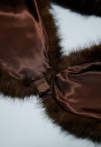 Fodera in satin marrone lucido con bordo in pelliccia marrone. L'intersezione presenta un dettaglio di attacco sottile, creando una texture stratificata.