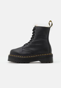 Bottes à lacets en cuir noir avec col en fourrure blanche douce, coutures jaunes, et semelle plateforme noire épaisse avec un motif de crampons robustes.