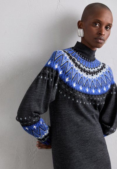 Pulover gri din tricot cu guler înalt, având un design pe piept în culorile albastru, negru și alb, și mâneci lungi puffate cu detalii de accent.
