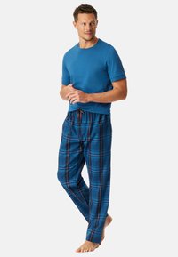 Blå t-shirt med kort ärm som matchas med rutig pyjamasbyxor i blå, röd och vit mönster. Avslappnad passform; dragsko i midjan.