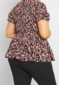 Schwarzes, blumiges Peplum-Top mit kurzen, puffärmeligen Ärmeln; verfügt über Muster in Pink, Gelb und Weiß; strukturierter Stoff mit gerafftem Taillendetail.