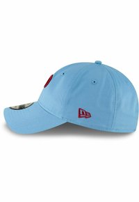 Gorra de béisbol azul claro con acentos rojos. Presenta una corona redondeada, visera curvada y un logo bordado en un lado. Material de algodón.