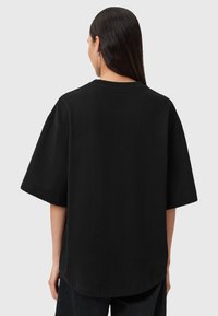 T-shirt nera oversize in cotone con maniche corte e colletto rotondo, caratterizzata da un orlo dritto e senza dettagli visibili sul retro.