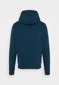 Sudadera de color azul oscuro con una textura suave, una capucha grande y puños acanalados. El diseño es simple, sin logotipos ni patrones visibles.