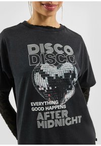 Zwart t-shirt met een hartvormige discobal graphic en de tekst "DISCO DISCO ALLES GOED GEBEUREN NA MIDDERNACHT" in het wit.