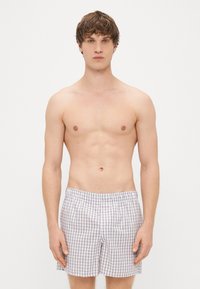 Boxeri cu un model tartan multicolor, talie elastică și croială lejeră. Materialul pare ușor și respirabil.