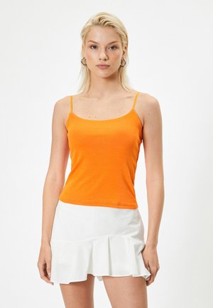 Orange fitted linne med tunna axelband, ihopparat med en vit volangminikjol. Slät textur, enkel design och enfärgad.