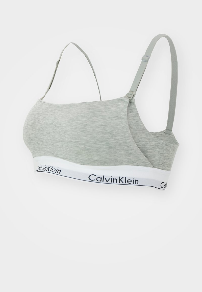 Calvin Klein pelēkā kokvilnas bralette ar regulējamām siksnām un baltu joslu ar melnu logos teksta. Gluda tekstūra un bezšuvju dizains.