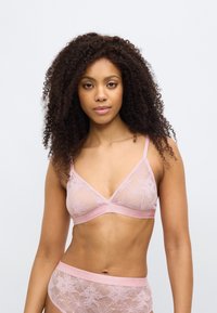 Διάφανο ροζ δαντελένιο σουτιέν με λουλουδάτα σχέδια, λεπτές τιράντες στους ώμους και ταινία ταιριαστή με το όνομα της μάρκας σε απαλό ροζ.