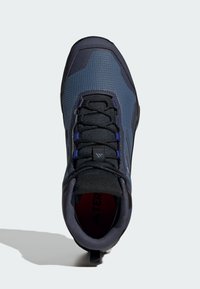 Mörkblå vandringsskor med textilämnen, förstärkt tå och svarta snören. Har en vadderad krage och en dragflik för enkel påtagning.