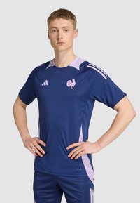 Námorný športový dres s svetloružovými akcentmi, obsahujúci logo kohúta a tri pruhy na pleciach. Vyrobený z priedušného materiálu.