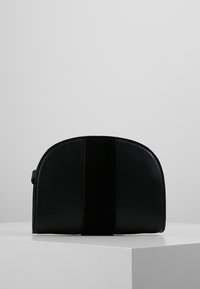 Borsa in pelle nera dalla forma arrotondata e con un pannello centrale in suede. Texture liscia con una leggera lucentezza, caratterizzata da un design minimalista.