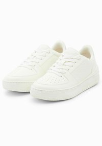 Baskets blanches avec un dessus texturé, des lacets plats, un bout perforé et une semelle épaisse. Présente un logo discret sur le côté.