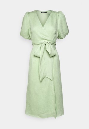 Jasnozielona lniana sukienka kopertowa z fakturowanym wykończeniem, krótkimi bufiastymi rękawami i dopasowanym paskiem wiązanym w talii. Długość midi.