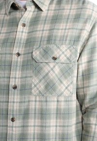 Chemise à carreaux verte et crème ; dispose d'un design à boutons, d'une poche poitrine et d'une texture à motifs avec des accents bleus. Fabriquée en flanelle.