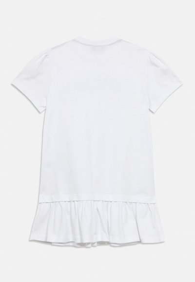 T-shirt blanc à manches courtes avec un détail à volants sur l'ourlet en bas, présenté de dos sur un fond uni.