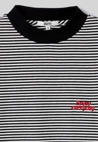 Haut à manches courtes noir et blanc à rayures avec une texture côtelée. Présente un col noir et un texte brodé rouge "Profitez de chaque jour."