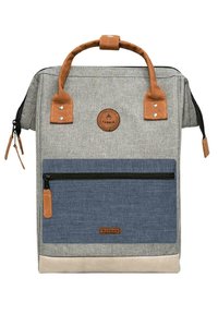 Grauer Stoffrucksack mit einer blauen Reißverschlusstasche, braunen Lederausschnitten und oberen Griffen. Verfügt über ein rundes Logo und ein robustes Design.