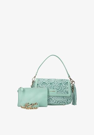 Sac à main vert menthe avec détails au crochet, pompon détachable et petite pochette assortie avec chaîne dorée sur fond blanc.